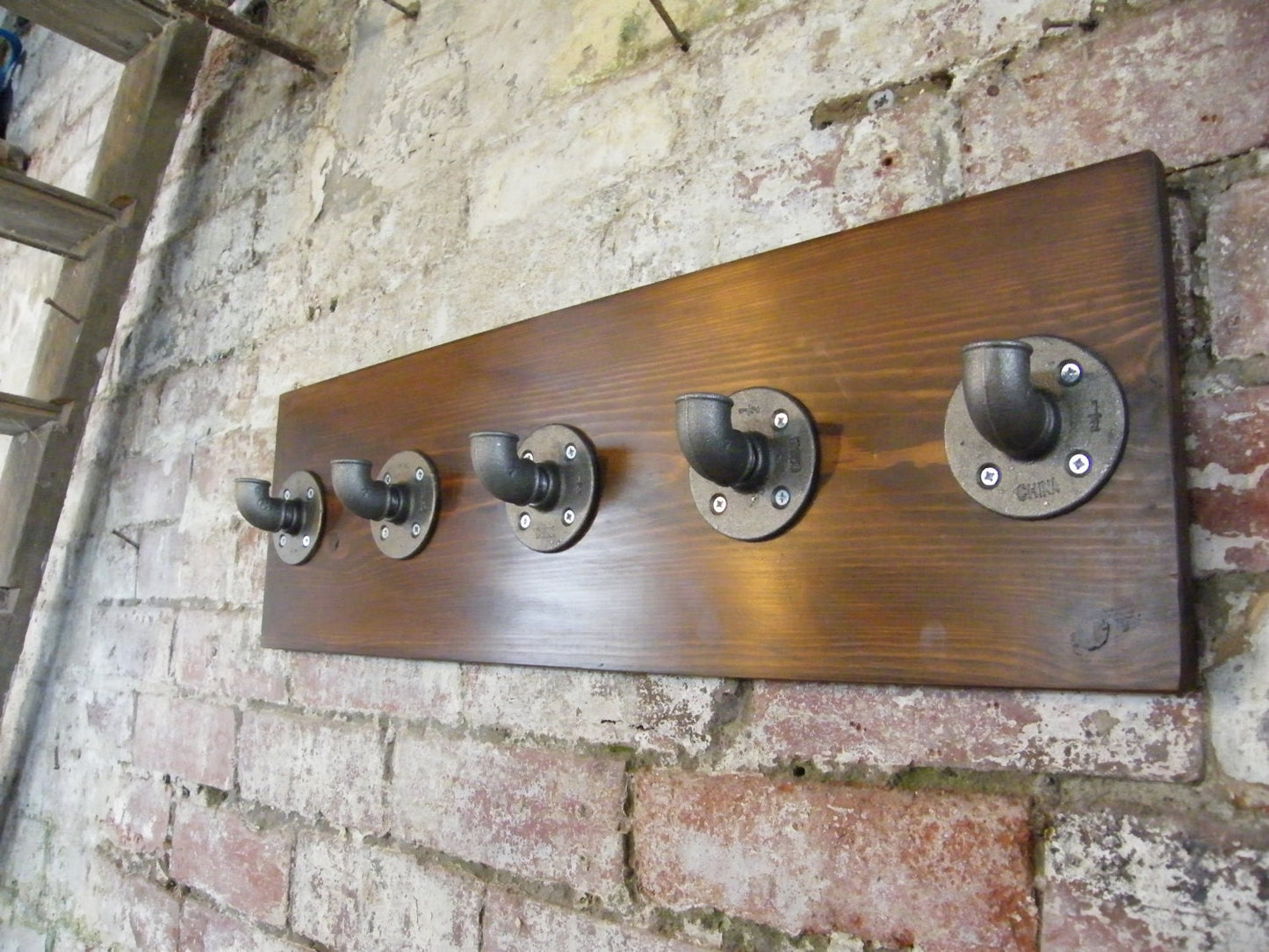 a coat rack using malleable iron pipe fittings, with a walnut style finish backing plate