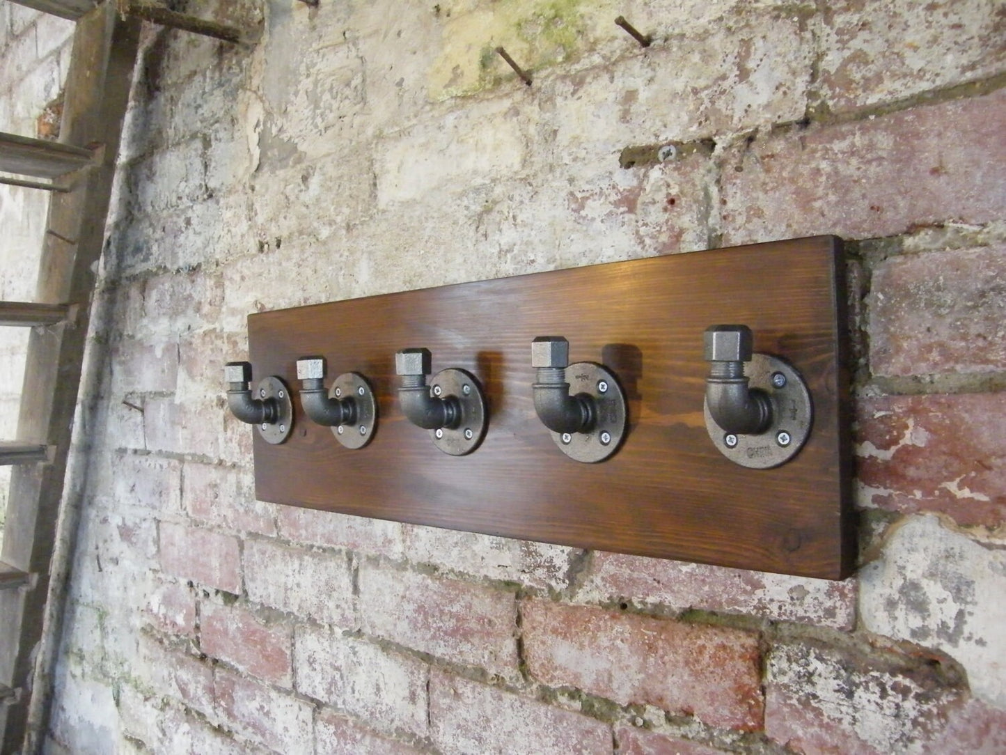 a coat rack using malleable iron pipe fittings, with a walnut style finish backing plate