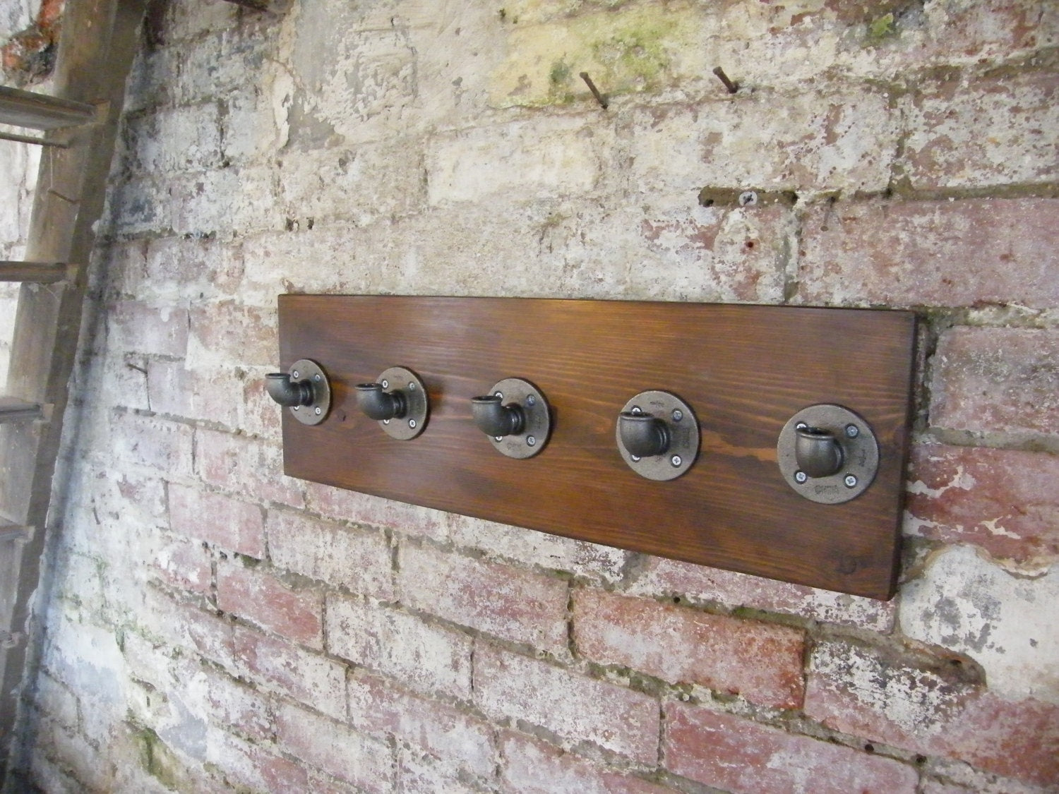 a coat rack using malleable iron pipe fittings, with a walnut style finish backing plate