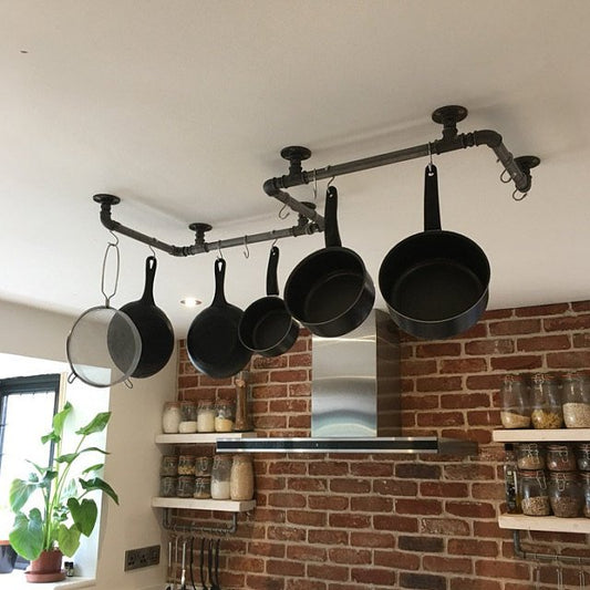 a large S shaped pan rack suspended from the ceiling, made from industrial gas pipe fittings, threaded pipe, stainless steel hooks, holds 10 pans